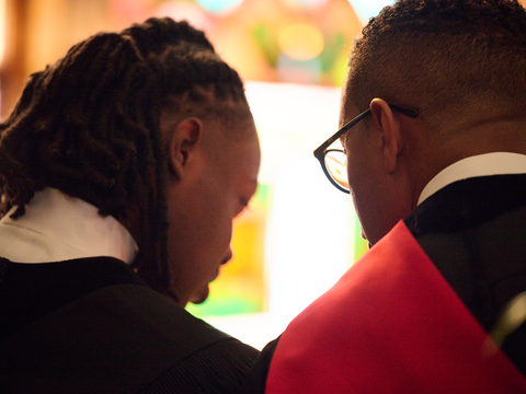 A student talks to his mentor in a chruch. Their backs are to the camera