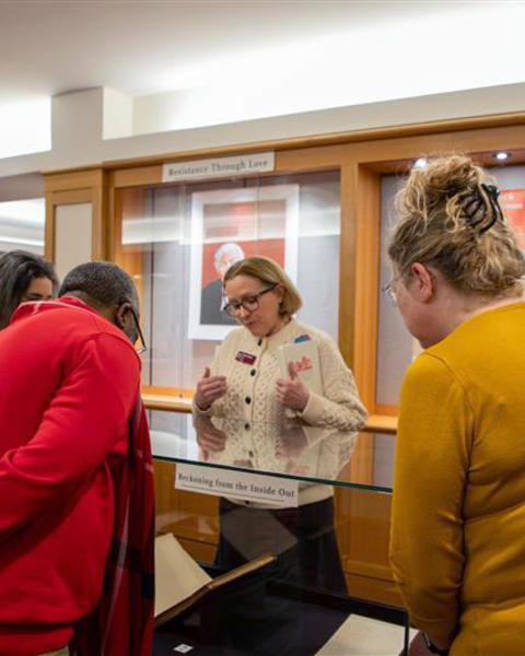 Viewers lean in to look at the exhibit cases
