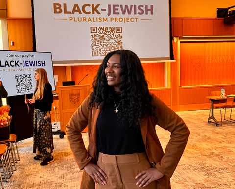Janeen Green stands in front of a screen that says Black-Jewish Pluralism Project
